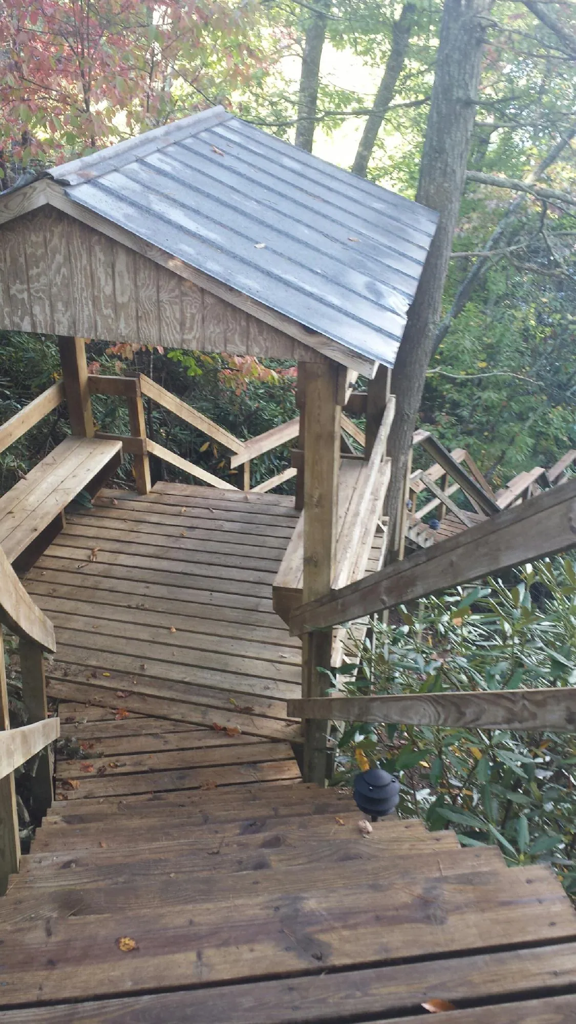 Metal roofed shelter over wooden steps on a wooded walkway — Skylight Repair & Installation work by our crew in Lebanon